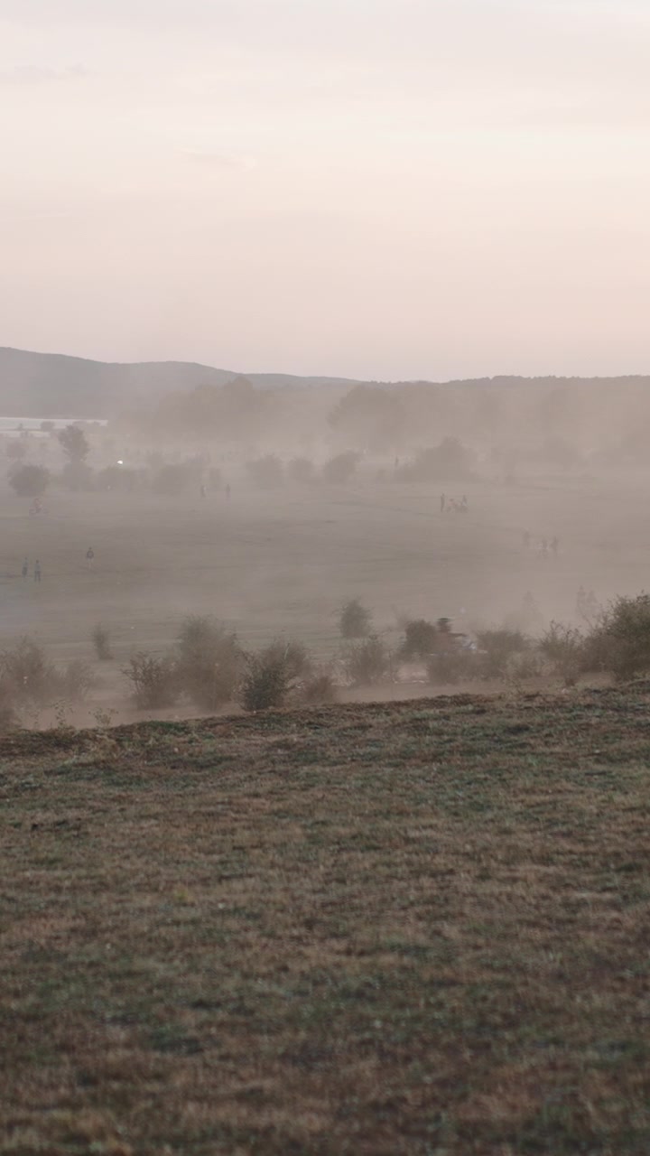 Motorcyclists Riding Through Dusty Field at Sunset