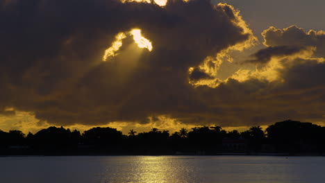 sol dorado fluyendo a través del agujero en las nubes sobre el agua del sur de florida