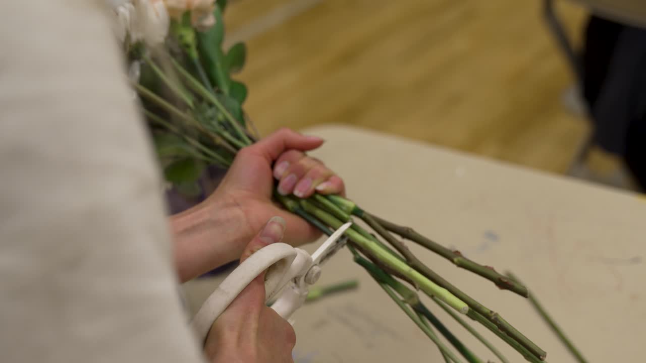 A florist clips the stems of flowers in a bouquet before tying them together