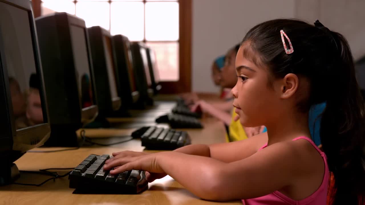 Little girl using computer in classroom in school