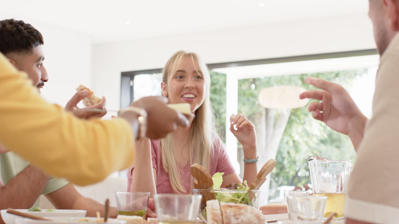 Laughing and enjoying meal, young friends having lunch together at home