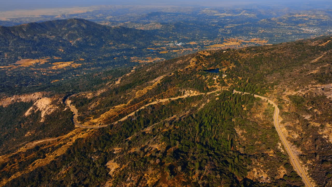 Four lane road crossing the mountains. Sunny view of the Sierra National Forest in USA from aerial perspective.