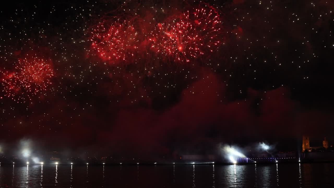 어두운 하늘에서 화려한 반사와 함께 화려한 불꽃놀이와 밝은 빛이 물 속에 아름답게 반사됩니다.