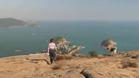 girl and dog walking away from camera towards mountain view of shek o and big wave bay, dragons back, hong kong