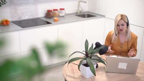 woman working with laptop in bright kitchen. covid-19 coronavirus. social distancing