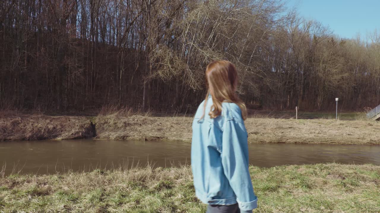 Mädchen spaziert an einem Fluss im Wald.