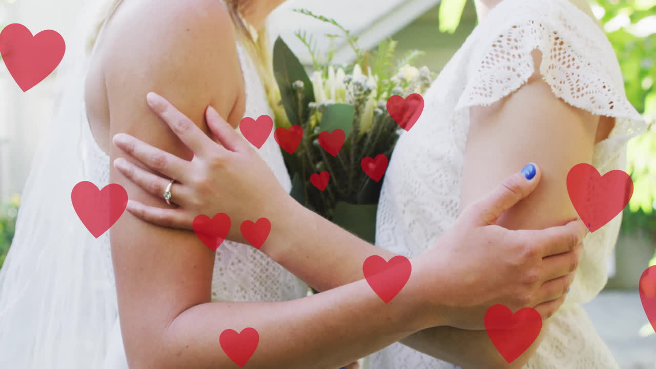 Animation of hearts over diverse female married couple embracing