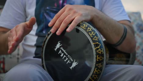 primer plano de un tipo en un tambor árabe, tocando la darbuka con vibraciones orientales