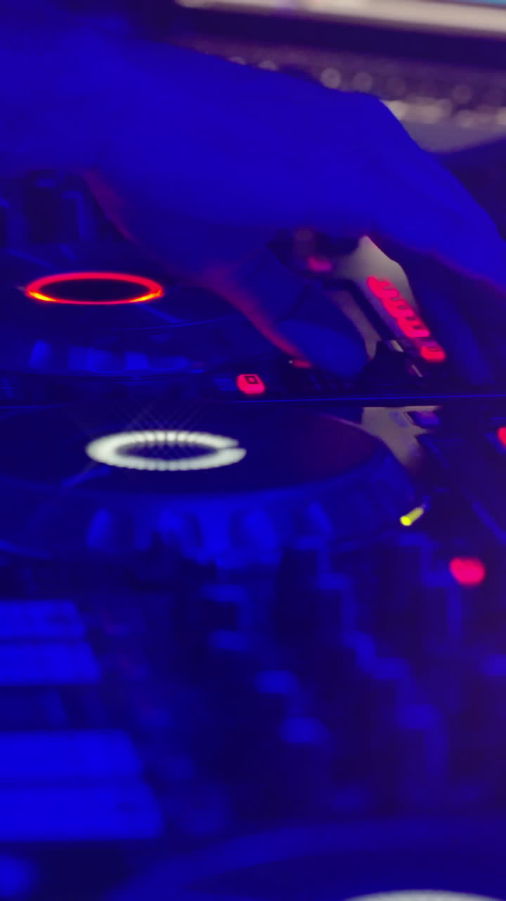 Primo piano di un mixer da DJ con luci lampeggianti e una mano che aziona i controlli