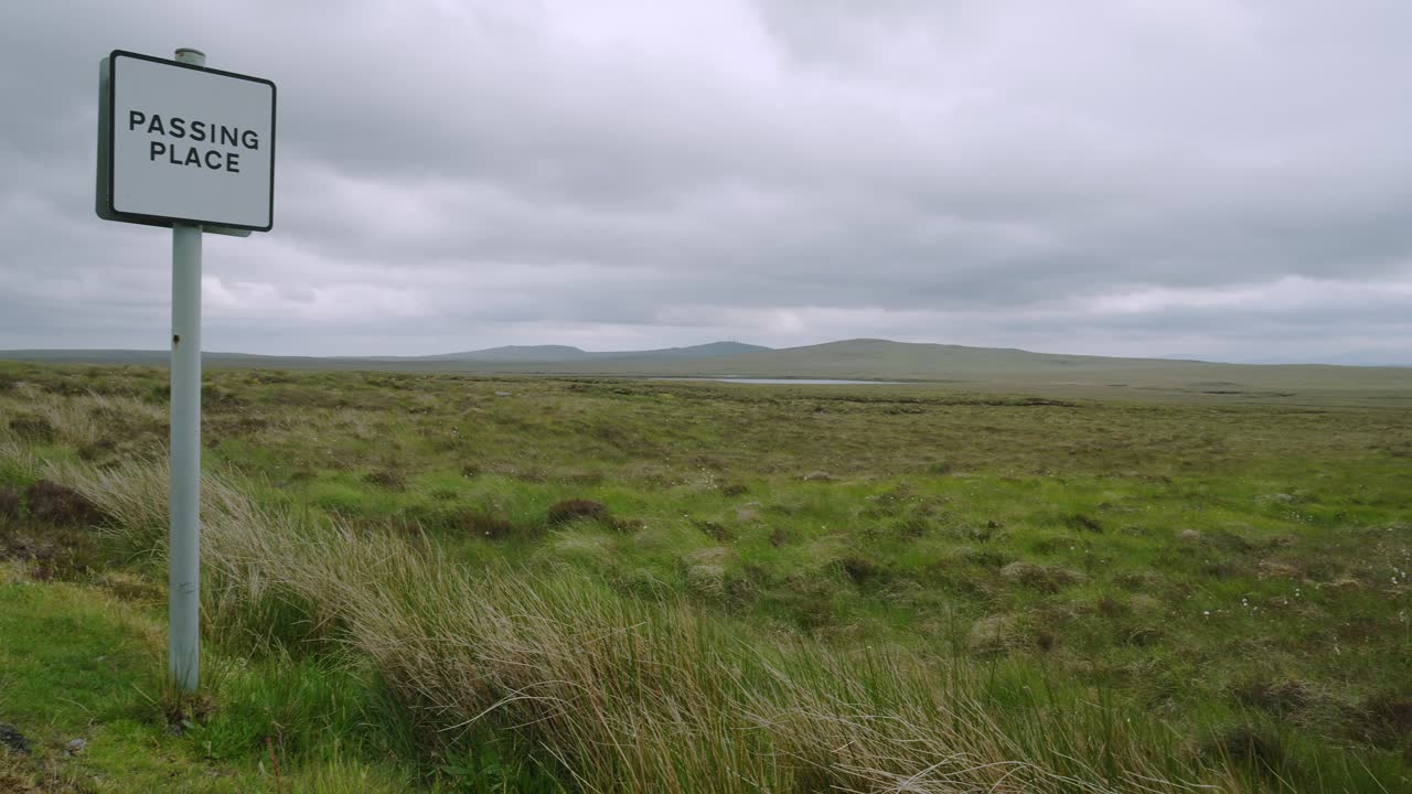 Panning shot from a roadside passing place sign to a moorland peat bank