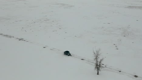 wide aerial tracking utv side by side driving through snowy field winter, 4k