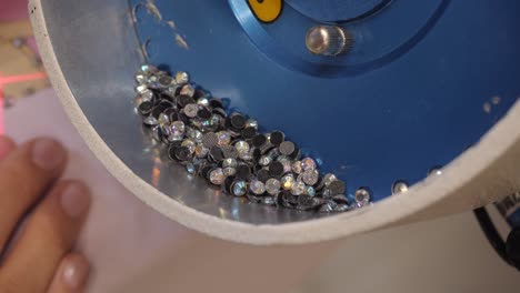 the process of applying rhinestones to clothes using an industrial machine.