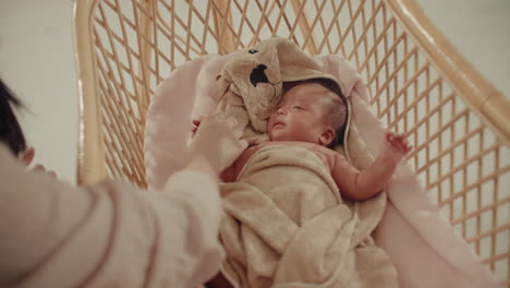 mother cuddles taking care of newborn baby in wooden cradle, playing with parents at home , family parenthood moments