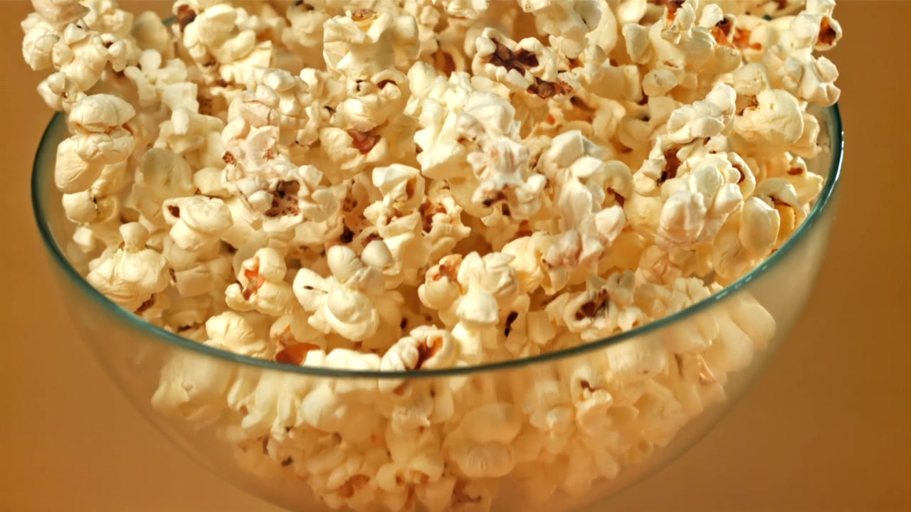 Popcorn fresco che si versa in una ciotola di vetro al rallentatore