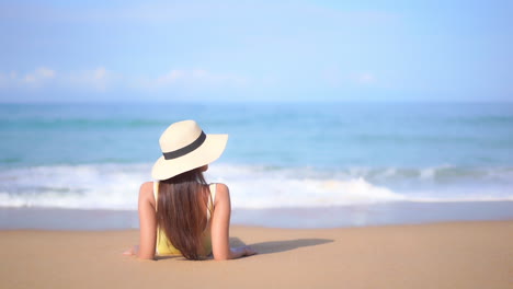 Back-of-Young-Woman-Sunbathing-on-Sandy-Beach-in-Front-of-Tropical-Sea-Waves-and-Endless-Skyline-on-Sunny-Day,-Full-Frame-Slow-Motion