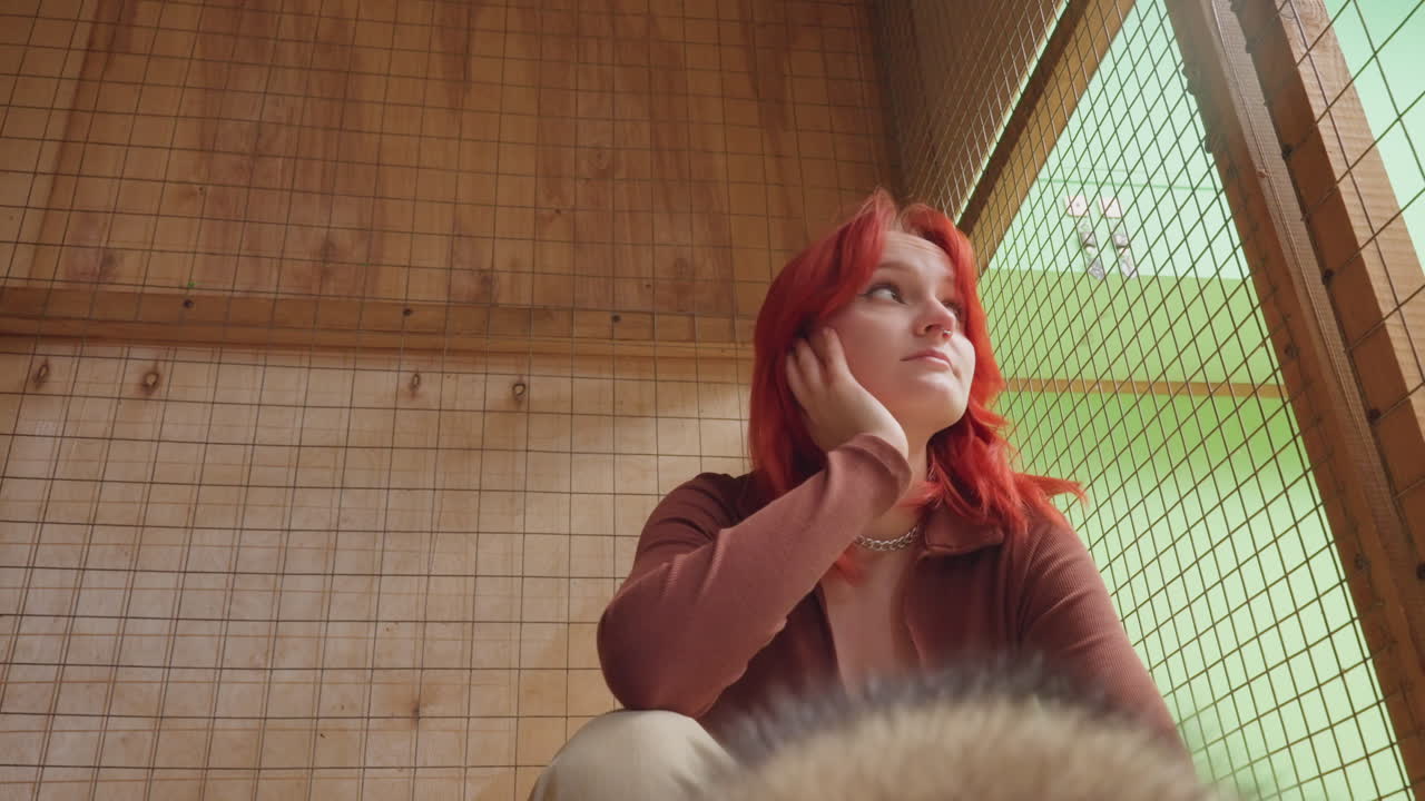 cozy wooden cabin portrait white woman artist with red hair and dog fur in foreground, leaning chin on hand, casual sweater, bamboo wall backdrop, warm sunlight through window, contemplative
