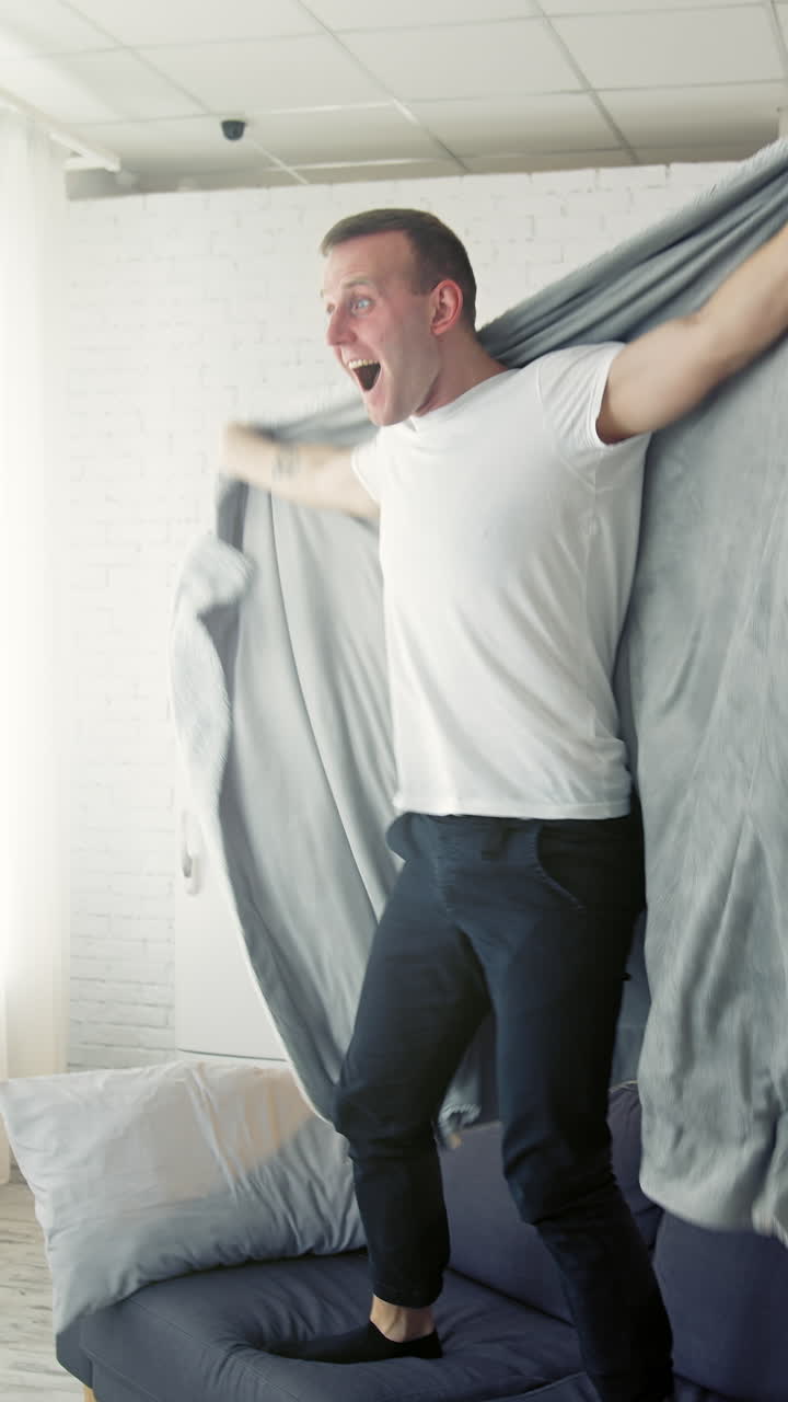 Happy man on bed. Young man waking up and began to joy waving blanket. Cheerful man recovered from the disease. Healthcare concept. Vertical video