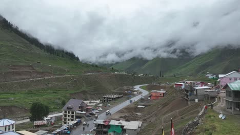 a serene view of a small, remote tourist destination batakundi, naran, pakistan with the clouds covering the mountains in the background