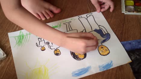 a child paints a drawing on the floor with watercolors. drawing depicting a family 01