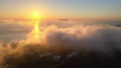 aerial sunrise over clouds and sea in santorini island, greece