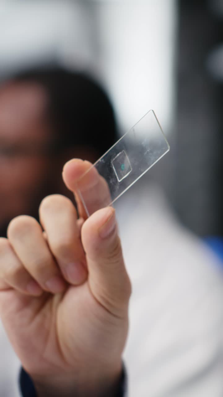 Vertical video Senior microscopist examining microscope glass slide in laboratory