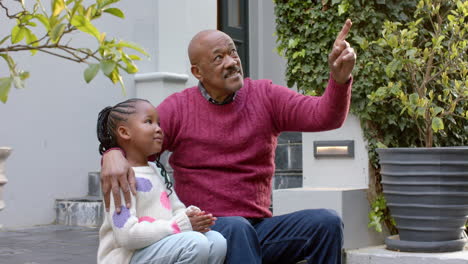 Feliz-Abuelo-Y-Nieta-Afroamericanos-Sentados-Y-Hablando-En-El-Jardín,-Cámara-Lenta