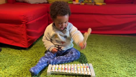 two year old afro european exotic baby playing a toy xylophone at home