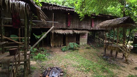 A traditional elevated longhouse with thatched roof and walls stands supported by wooden stilts within Mari Mari cultural village, Kota Kinabalu, Malaysia