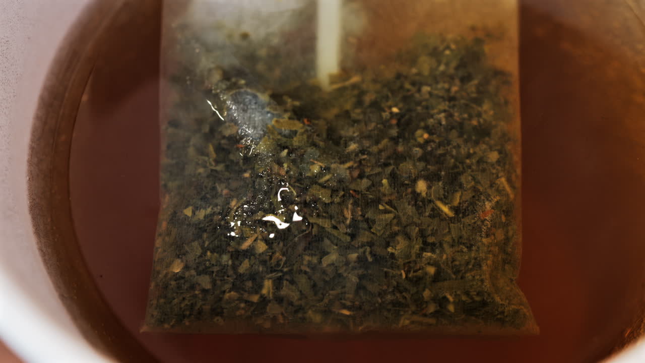 Close up of a tea bag brewing into a red cup
