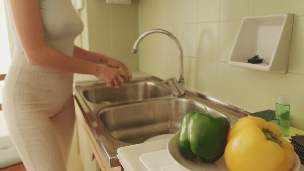 Mujer lavando verduras en la cocina