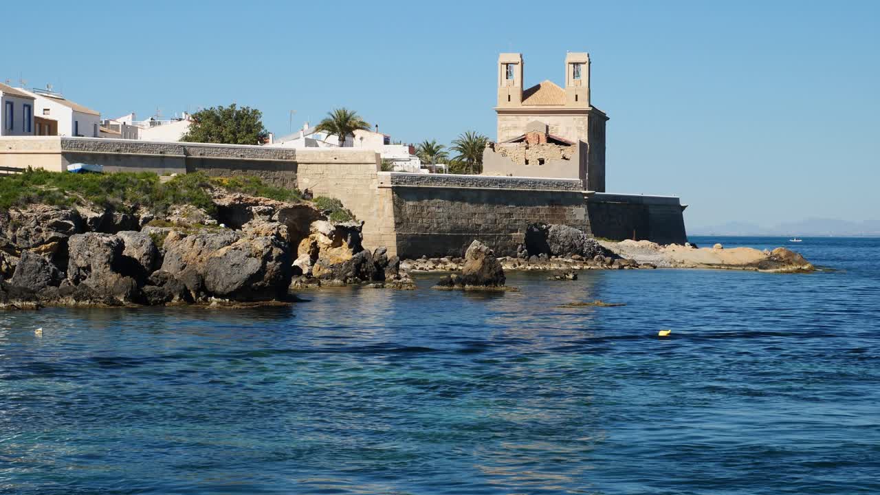 Gereja Santo Petrus dan Santo Paulus, serta tembok yang terlihat dari pelabuhan. Pulau Tabarca. Spanyol. Gerak lambat x0,5.