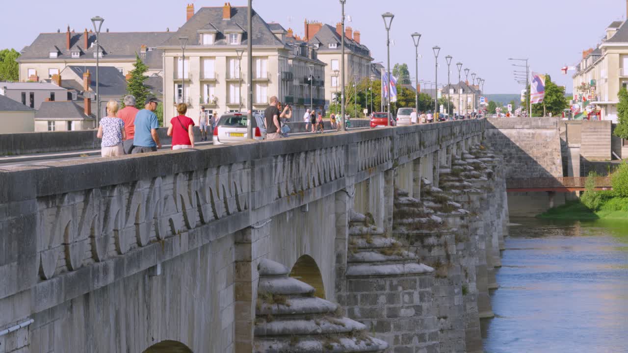 Camera Panning Up to Reveal Tourists on Bridge in Saumur During Summer Vacation with Cars and Historic Buildings Over Loire River 4K