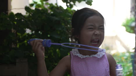 asian girl blowing bubbles with a bubble wand, portrait close up