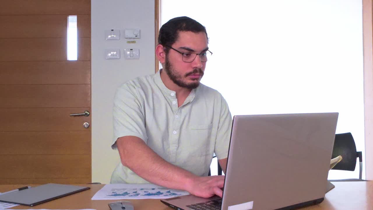 Attentive Jewish Businessman with Glasses Focused on Reading Paperwork