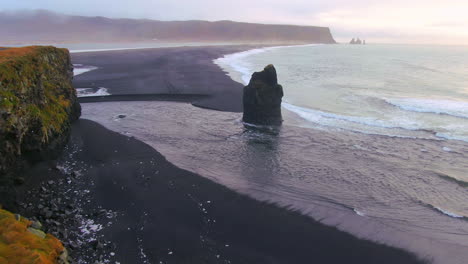 drone cinematográfico aéreo panorámica impresionante amanecer temprano en invierno en la playa de arena negra apóstoles fuego y hielo océano junto a dyhrolaey faro reynisfjara islanda