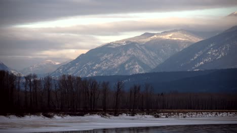 Lapso-De-Tiempo-De-Nubes-Espesas-En-La-Luz-De-La-Hora-Dorada-Sobre-Picos-Nevados-Y-El-Río-Congelado-North-Thompson-Cerca-De-Little-Fort,-BC