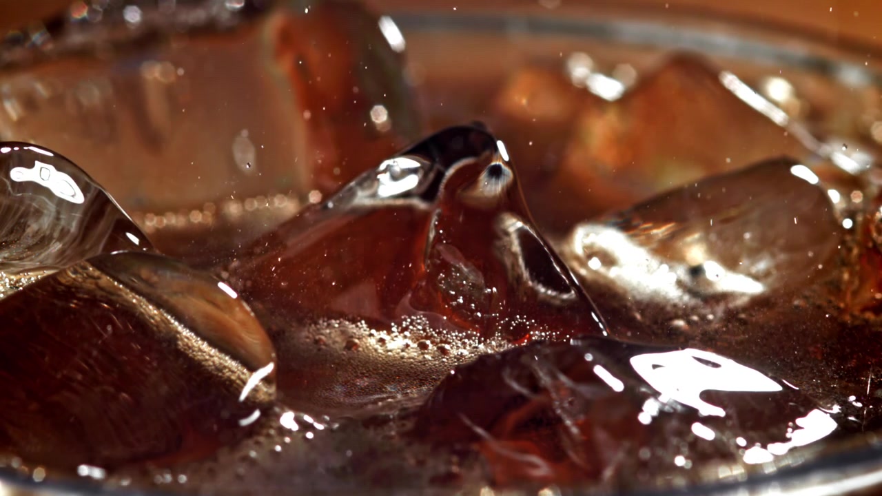 Scatto macro di una bevanda alla cola rinfrescante con ghiaccio e bollicine
