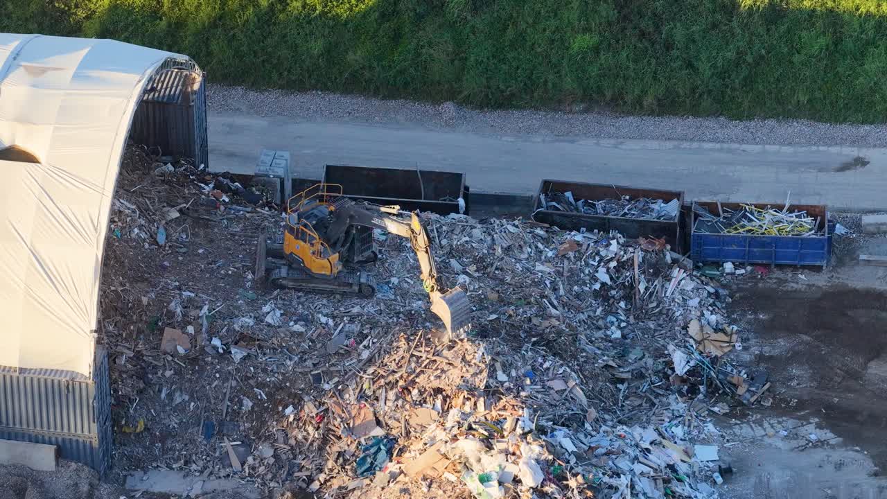 Ripresa da drone di un escavatore industriale che sposta detriti presso un centro di gestione dei rifiuti nella Gold Coast.