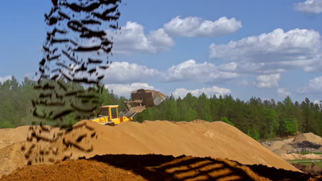 slow motion shot of falling sand and rocks on construction site with digger in background