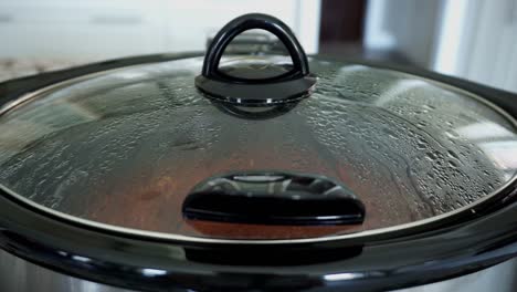 slow cooker pot cooking pulled pork with condensation on the lid from boiling water and juices