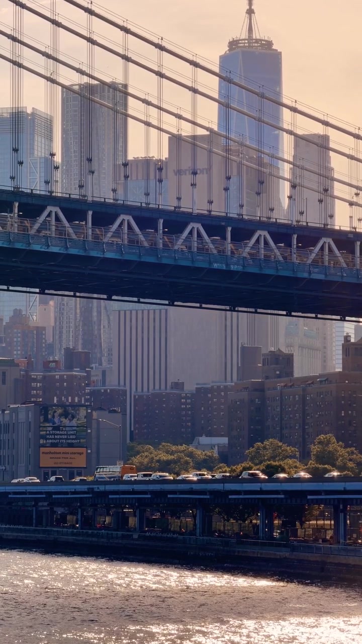 New York, USA, 22 maggio 2026: Il Ponte di Manhattan incornicia il traffico cittadino e i grattacieli del centro. Vista verticale della campata a traliccio in acciaio con veicoli, edifici residenziali e uno skyline sfocato sullo sfondo.