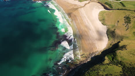 exótica costa de nueva zelanda con playa de arena y olas espumosas, vista aérea