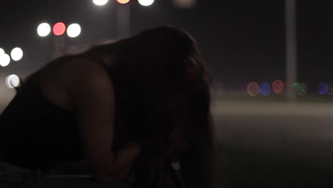 Close-up-Shot-Of-An-Emotional-Young-Woman-Sitting-At-The-Side-Of-The-Road-With-Cars-Passing-By