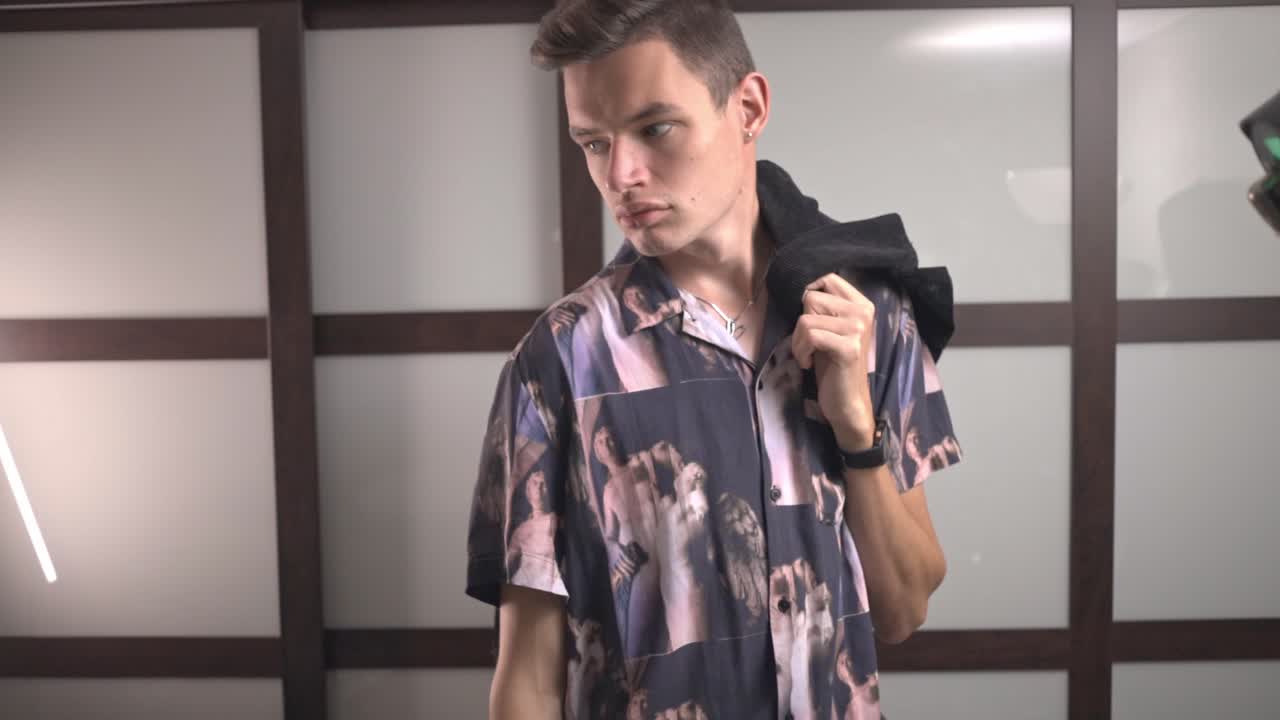 chico hipster con polo estampado con chaqueta sobre el hombro