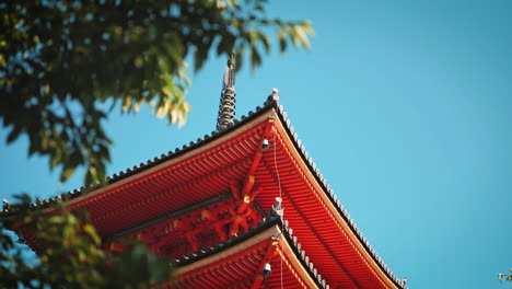 Vibrant-red-roof-of-the-Kiyomizu-dera-Temple-pagoda,-emphasizing-its-detailed-craftsmanship-against-a-clear-blue-sky