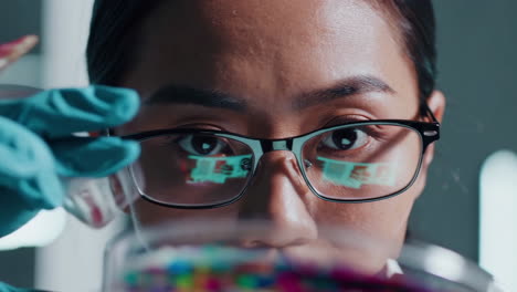 close-up of a scientist in a lab examining a sample with data reflected in her glasses