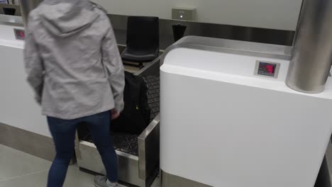 a shot of a woman weighing her luggage in an airport