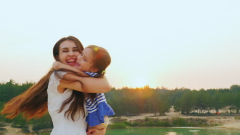 mom plays with her daughter hugging and turning it into sunset