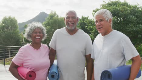 portrait of happy senior diverse people practicing yoga in garden at retirement home
