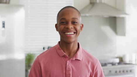 Video-Eines-Glücklichen-Afroamerikanischen-Jungen,-Der-In-Der-Küche-In-Die-Kamera-Blickt